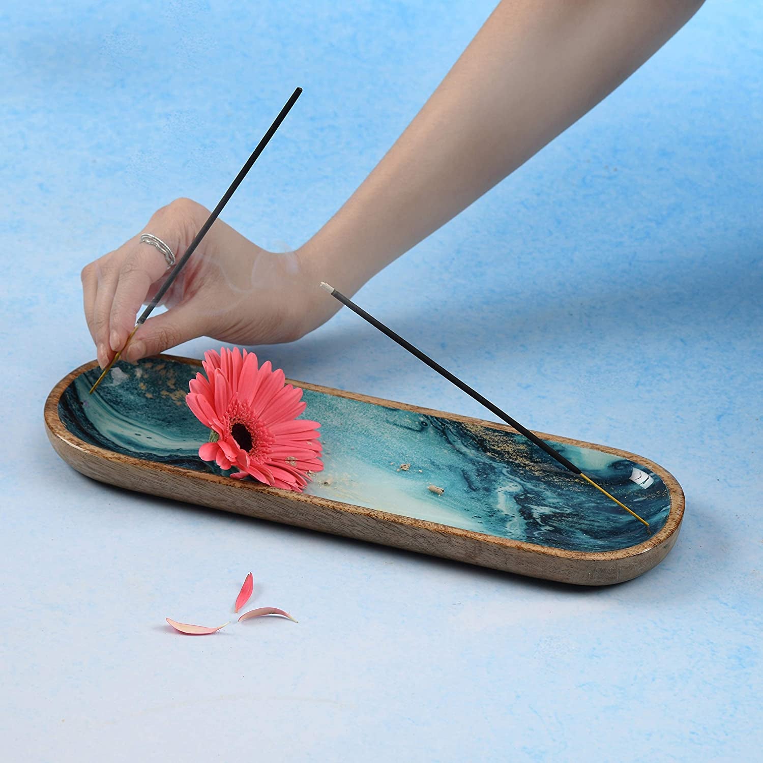 Blue marble incense holder with wood frame—hand placing incense stick, pink flower, and rising smoke for calming aromatherapy and elegant home decor
