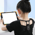 Child seated with tablet wearing posture corrector—promoting healthy sitting habits and ergonomic support during screen time