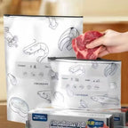 Hand placing raw steak into a reusable aluminum foil food storage bag labeled in Chinese, designed for freezing and preserving meat, with eco-friendly packaging shown on kitchen counter.