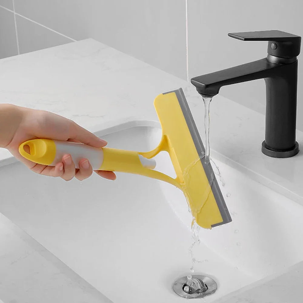 Yellow and white window squeegee being rinsed under faucet—rubber blade cleaned in white bathroom sink for easy maintenance and reuse