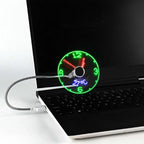 USB-powered LED clock fan connected to a laptop, featuring flexible metal gooseneck and spinning blades that display real-time analog clock with green hour markers and red hands; ideal for portable cooling and workspace personalization.