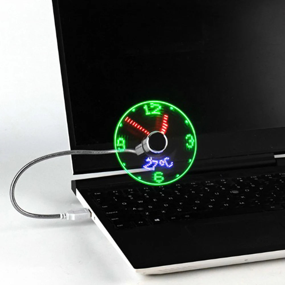 USB-powered LED clock fan connected to a laptop, featuring flexible metal gooseneck and spinning blades that display real-time analog clock with green hour markers and red hands; ideal for portable cooling and workspace personalization.