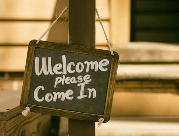 Rustic chalkboard-style welcome sign hanging outdoors with 'Welcome please Come In' message—ideal for creating a warm, inviting homepage atmosphere