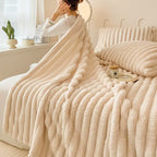 Cream-colored ribbed plush blanket and pillow set on a cozy bed—featuring a tea tray, bolster pillow, and soft natural light for a serene bedroom ambiance